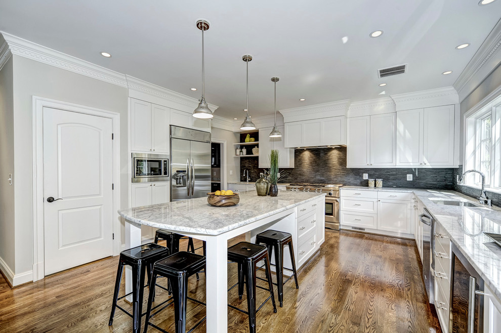 ワシントンD.C.にあるトランジショナルスタイルのおしゃれなアイランドキッチン (アンダーカウンターシンク、落し込みパネル扉のキャビネット、白いキャビネット、グレーのキッチンパネル、シルバーの調理設備) の写真