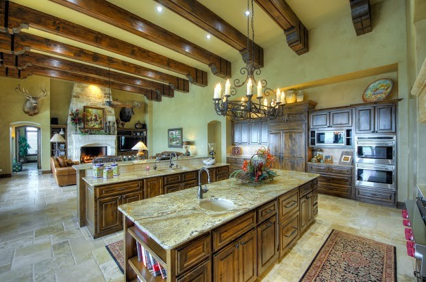 Foto på ett stort medelhavsstil kök, med luckor med upphöjd panel, skåp i mörkt trä, granitbänkskiva, rostfria vitvaror, klinkergolv i porslin, flera köksöar och beiget golv