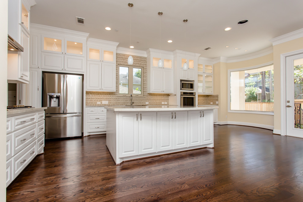 Inspiration for a large mediterranean l-shaped open plan kitchen in Houston with white cabinets, an island, a submerged sink, raised-panel cabinets, brown splashback, glass tiled splashback, stainless steel appliances, dark hardwood flooring and brown floors.