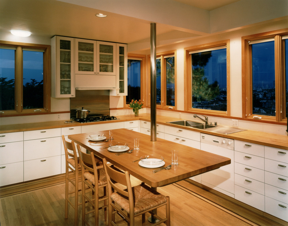 Diseño de cocina contemporánea con armarios tipo vitrina, encimera de madera y fregadero encastrado
