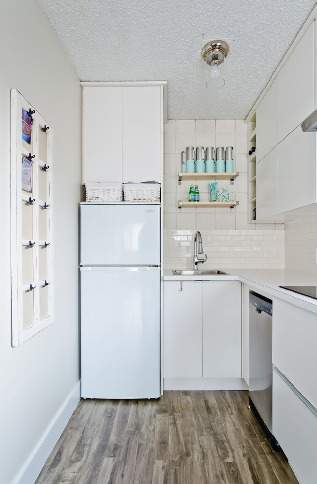 Kleine Moderne Küche mit Waschbecken, flächenbündigen Schrankfronten, weißen Schränken, Laminat-Arbeitsplatte, Küchenrückwand in Weiß, Rückwand aus Metrofliesen und Küchengeräten aus Edelstahl in Calgary