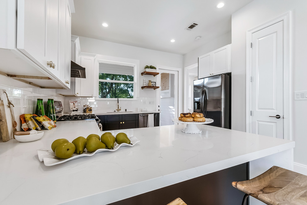 Photo of a medium sized retro u-shaped open plan kitchen in New Orleans with a submerged sink, shaker cabinets, white cabinets, composite countertops, white splashback, metro tiled splashback, stainless steel appliances, bamboo flooring, no island, brown floors and white worktops.