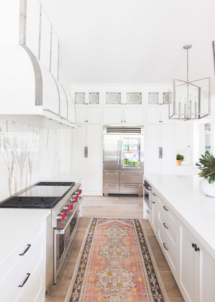 Foto di un cucina con isola centrale chic con ante in stile shaker, ante bianche, paraspruzzi multicolore, elettrodomestici in acciaio inossidabile e parquet chiaro