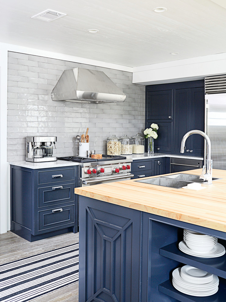 Bild på ett mellanstort eklektiskt kök, med en dubbel diskho, luckor med infälld panel, blå skåp, träbänkskiva, grått stänkskydd, stänkskydd i glaskakel, rostfria vitvaror, mellanmörkt trägolv och en köksö
