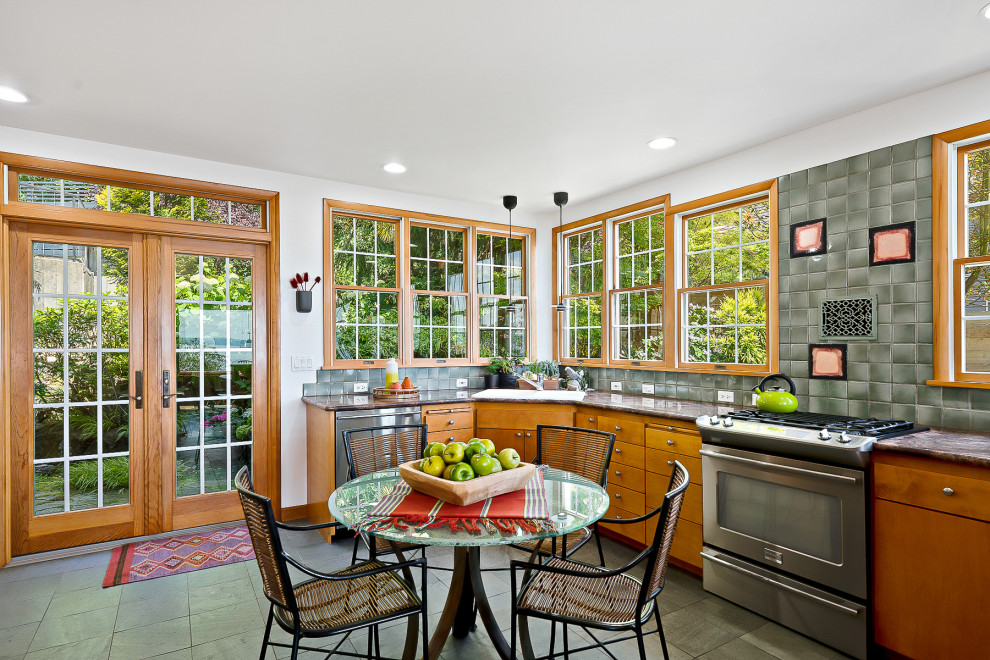 シアトルにあるトラディショナルスタイルのおしゃれなキッチン (フラットパネル扉のキャビネット、中間色木目調キャビネット、グレーのキッチンパネル、シルバーの調理設備、グレーの床、茶色いキッチンカウンター) の写真