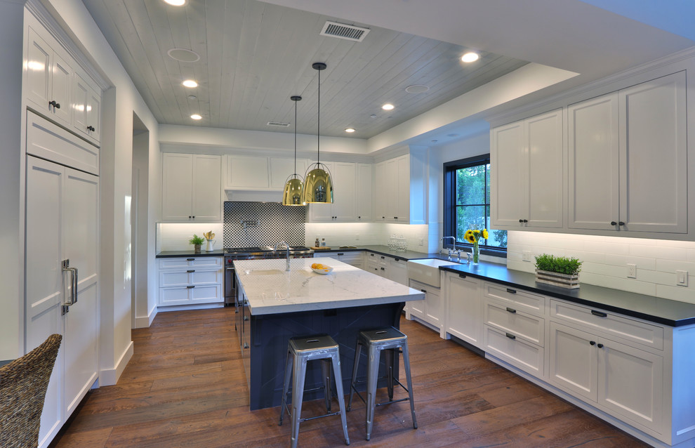 Inspiration for a large cottage u-shaped medium tone wood floor eat-in kitchen remodel in Los Angeles with a farmhouse sink, shaker cabinets, white cabinets, quartzite countertops, white backsplash, subway tile backsplash, paneled appliances and an island
