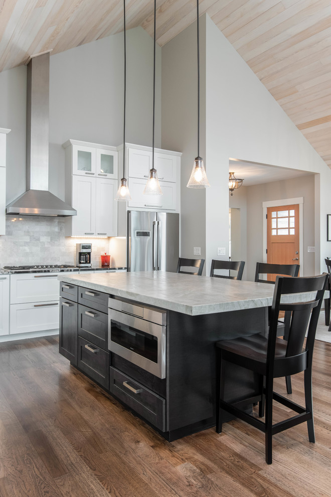 Example of a mid-sized arts and crafts l-shaped dark wood floor and brown floor eat-in kitchen design in Other with an undermount sink, shaker cabinets, white cabinets, granite countertops, gray backsplash, stone tile backsplash, stainless steel appliances, an island and multicolored countertops