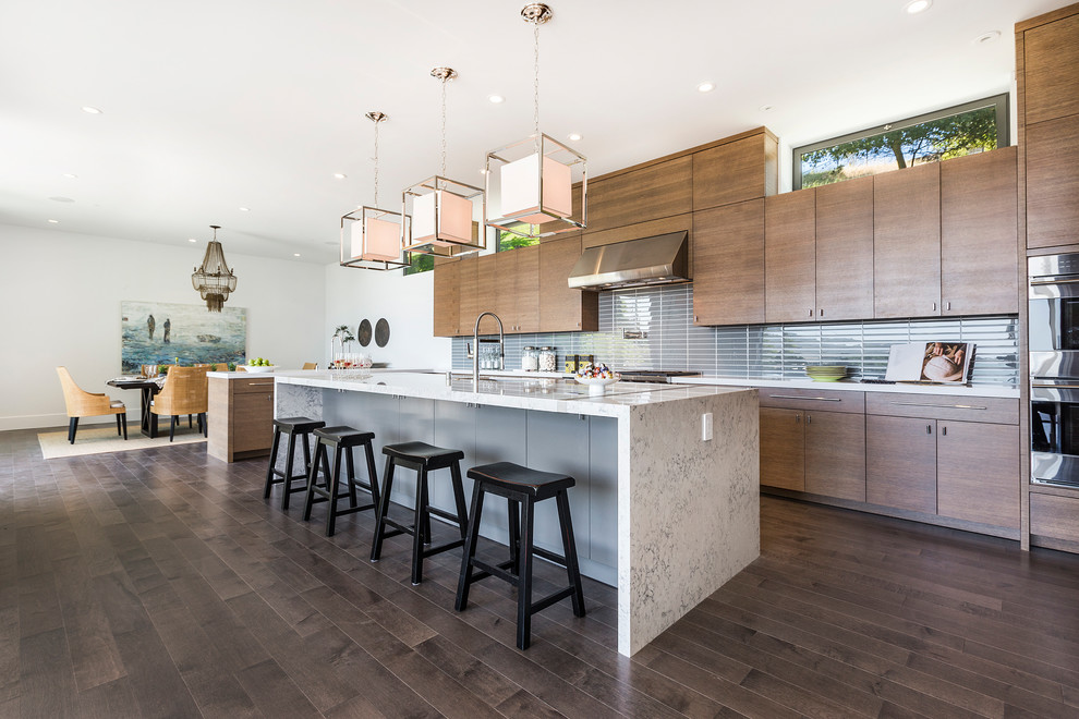 Design ideas for a contemporary galley kitchen in Sacramento with flat-panel cabinets, dark wood cabinets, grey splashback, stainless steel appliances, dark hardwood flooring, an island, brown floors and white worktops.