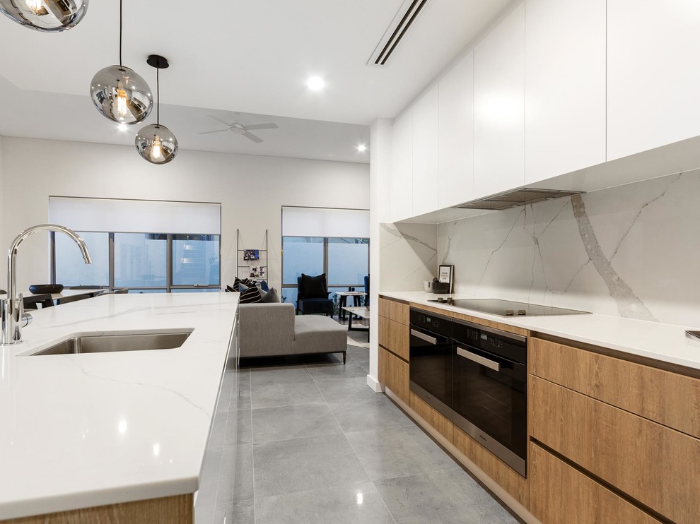 Mid-sized trendy galley ceramic tile and gray floor open concept kitchen photo in Perth with an undermount sink, flat-panel cabinets, medium tone wood cabinets, solid surface countertops, white backsplash, ceramic backsplash, black appliances, an island and white countertops