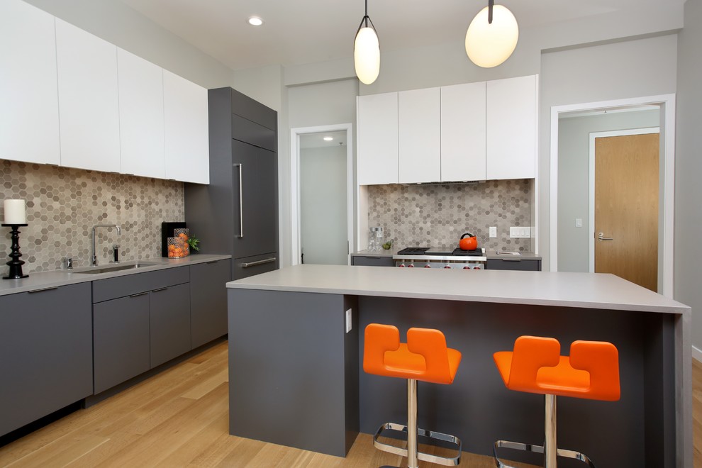 Exempel på ett avskilt modernt kök, med en undermonterad diskho, släta luckor, grå skåp, flerfärgad stänkskydd, stänkskydd i mosaik, integrerade vitvaror, ljust trägolv och en köksö