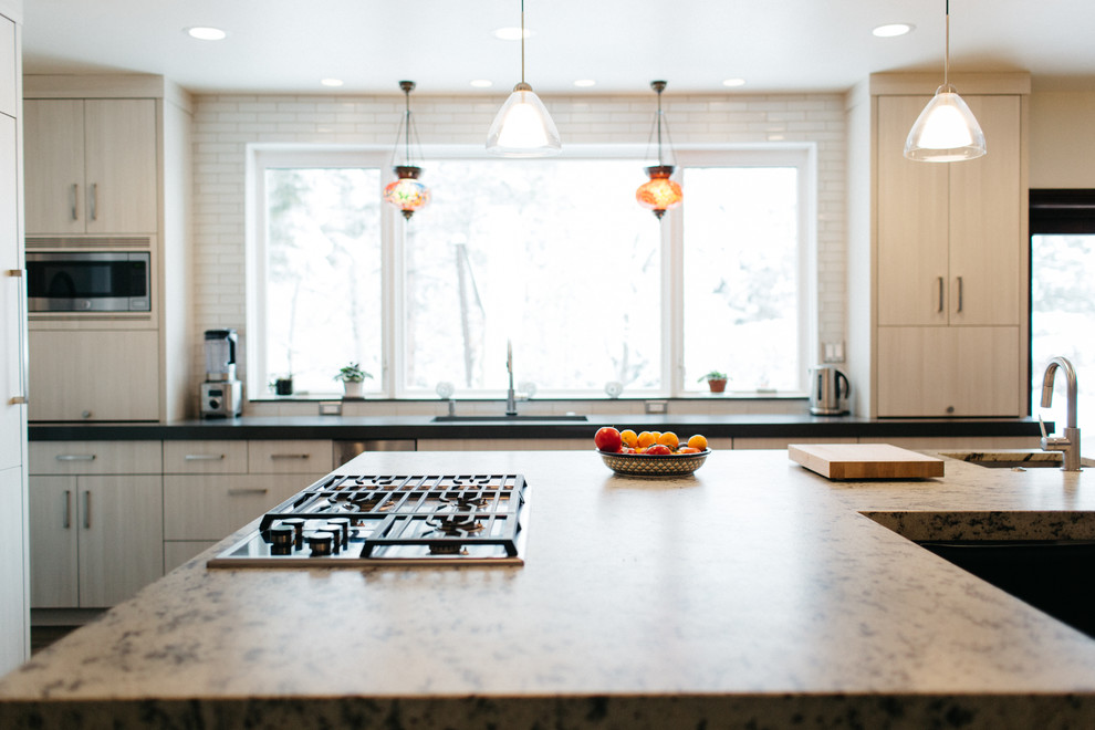 シアトルにある広いトランジショナルスタイルのおしゃれなキッチン (アンダーカウンターシンク、フラットパネル扉のキャビネット、白いキャビネット、御影石カウンター、パネルと同色の調理設備、濃色無垢フローリング、茶色い床、白いキッチンパネル、ガラスタイルのキッチンパネル) の写真