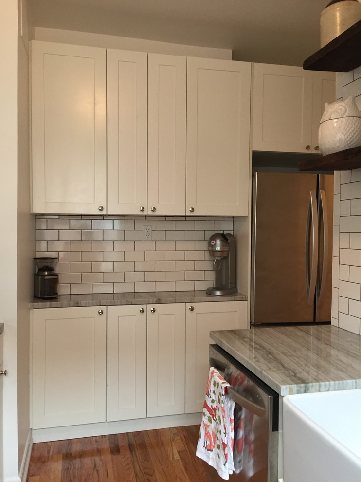 Bild på ett litet eklektiskt kök, med en rustik diskho, skåp i shakerstil, vita skåp, bänkskiva i kvartsit, vitt stänkskydd, stänkskydd i tunnelbanekakel, rostfria vitvaror och ljust trägolv