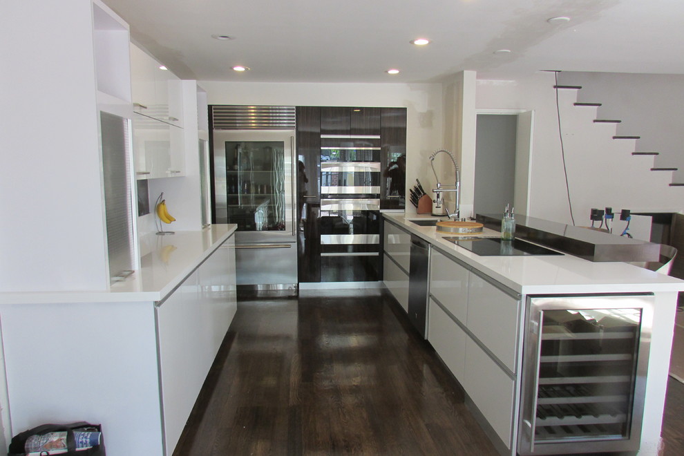 Modern inredning av ett mellanstort kök, med en undermonterad diskho, släta luckor, vita skåp, bänkskiva i kvartsit, rostfria vitvaror och en köksö