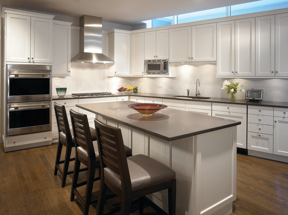 Immagine di una cucina minimal con ante con riquadro incassato, ante bianche, paraspruzzi beige e elettrodomestici in acciaio inossidabile