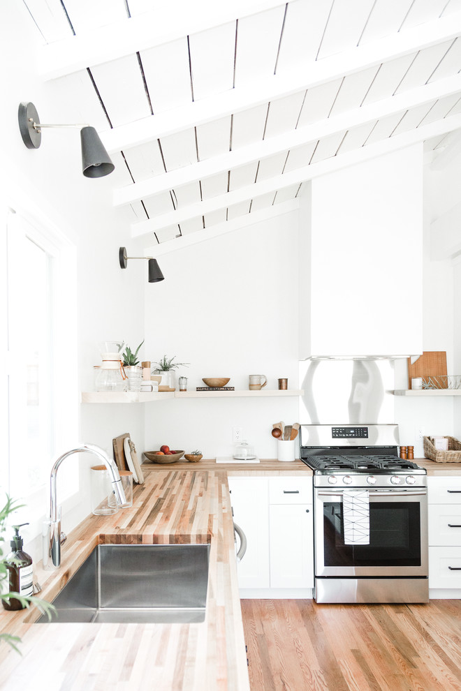 Imagen de cocina costera con armarios estilo shaker, puertas de armario blancas y encimera de madera