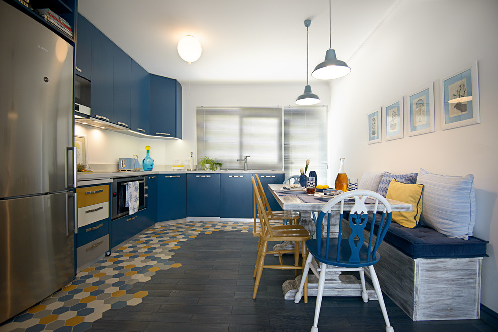 Maritime Wohnküche in L-Form mit flächenbündigen Schrankfronten, blauen Schränken, Küchengeräten aus Edelstahl und buntem Boden in Sonstige