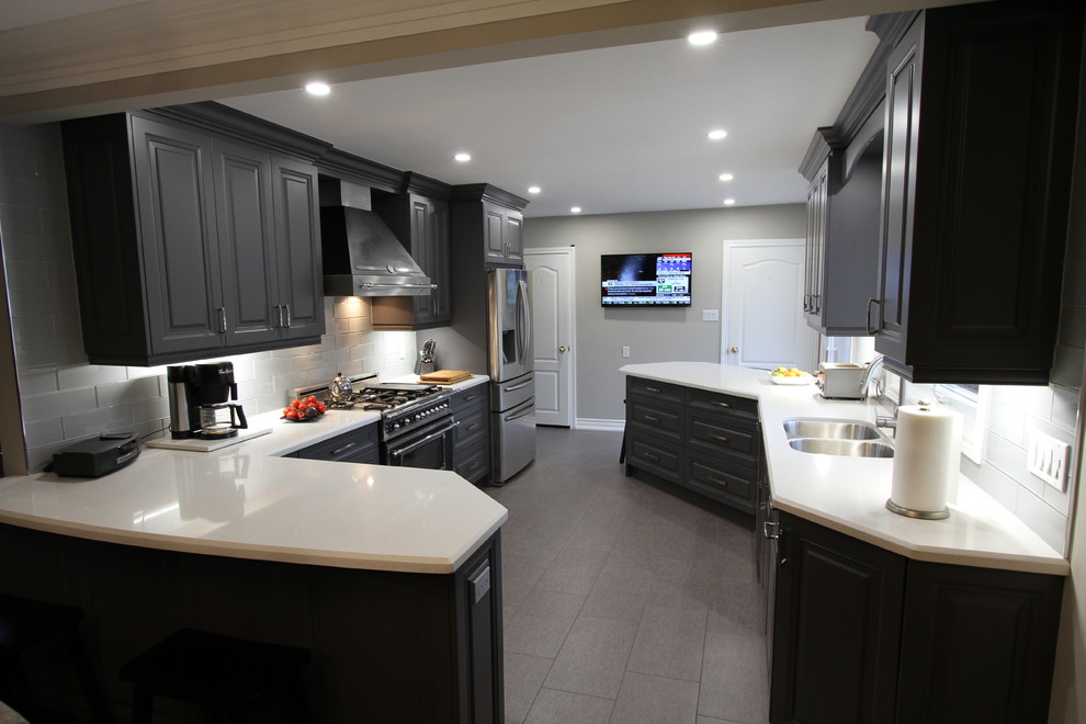 Foto de cocina comedor contemporánea de tamaño medio con fregadero bajoencimera, armarios con paneles con relieve, puertas de armario grises, encimera de cuarzo compacto, salpicadero verde, salpicadero de vidrio templado, electrodomésticos de acero inoxidable, suelo de linóleo y península