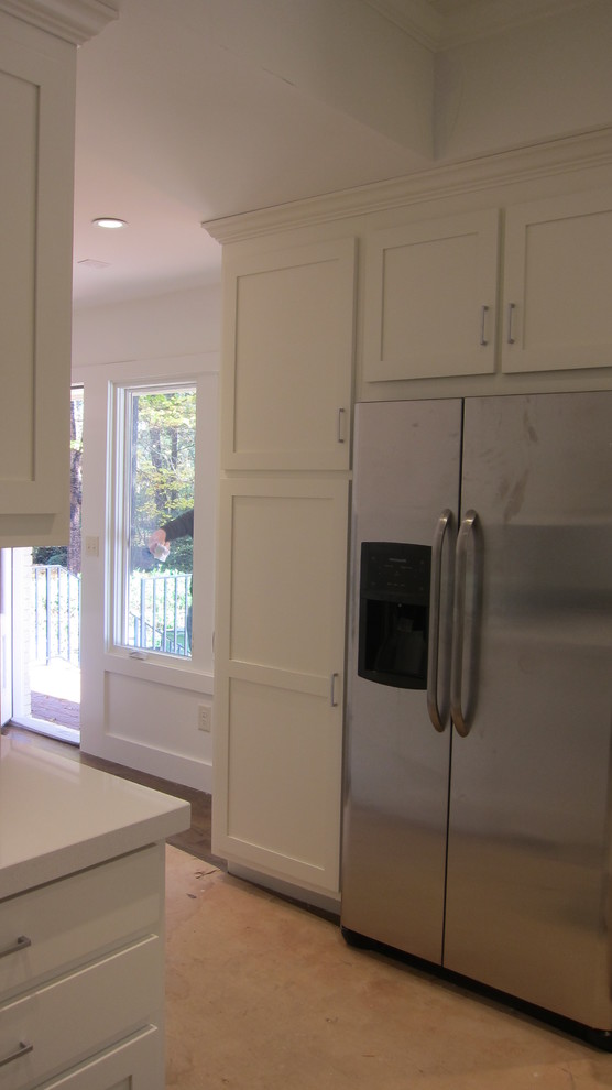 Klassisk inredning av ett litet vit vitt kök med öppen planlösning, med en nedsänkt diskho, släta luckor, skåp i ljust trä, bänkskiva i kvarts, blått stänkskydd, stänkskydd i keramik, rostfria vitvaror, mellanmörkt trägolv, en köksö och brunt golv