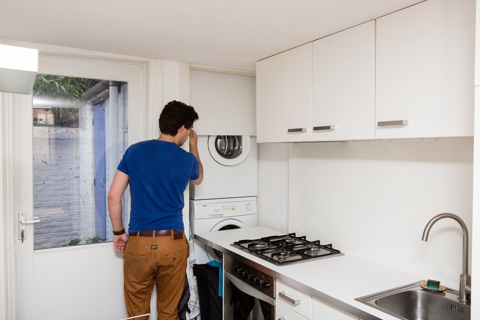 Cette photo montre une cuisine moderne avec un placard à porte plane, un évier posé, des portes de placard blanches et machine à laver.