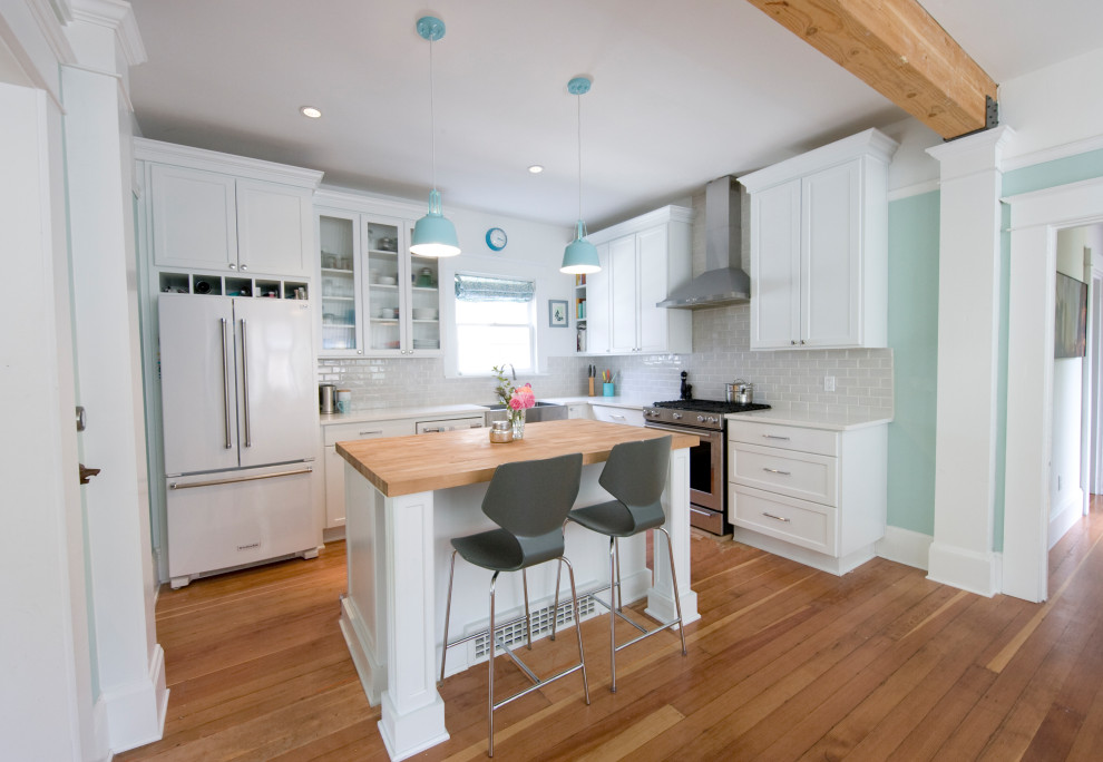 Idéer för ett mellanstort lantligt vit kök, med en rustik diskho, luckor med infälld panel, vita skåp, bänkskiva i kvarts, grått stänkskydd, stänkskydd i keramik, vita vitvaror, mellanmörkt trägolv, en köksö och brunt golv