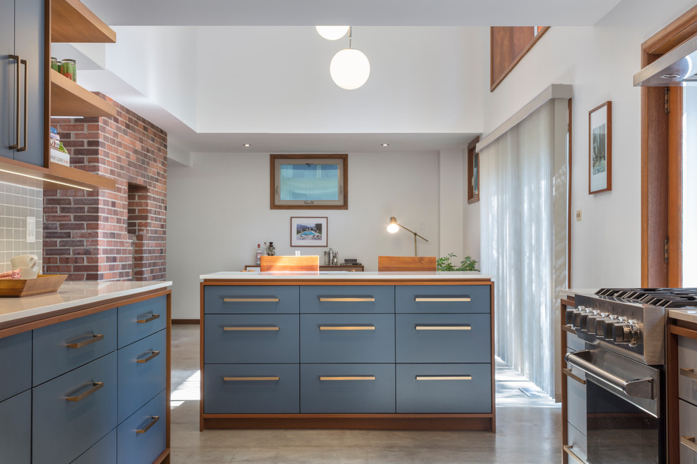 Mid-sized 1960s galley concrete floor and gray floor eat-in kitchen photo in Kansas City with an undermount sink, flat-panel cabinets, blue cabinets, quartz countertops, gray backsplash, porcelain backsplash, stainless steel appliances and an island