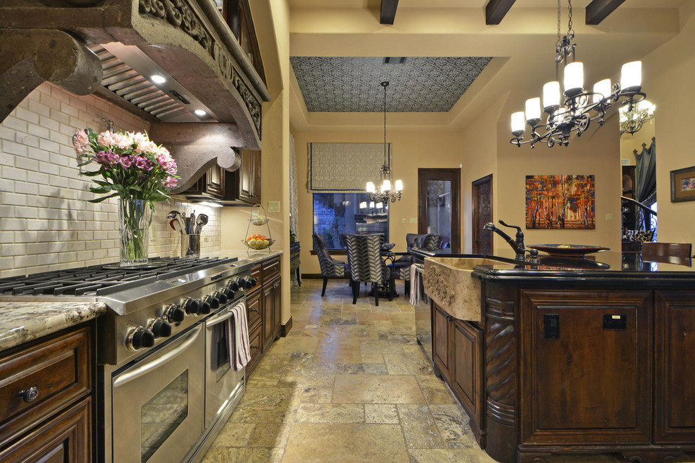 Large tuscan l-shaped travertine floor eat-in kitchen photo in Austin with a farmhouse sink, dark wood cabinets, granite countertops, white backsplash, stainless steel appliances and an island