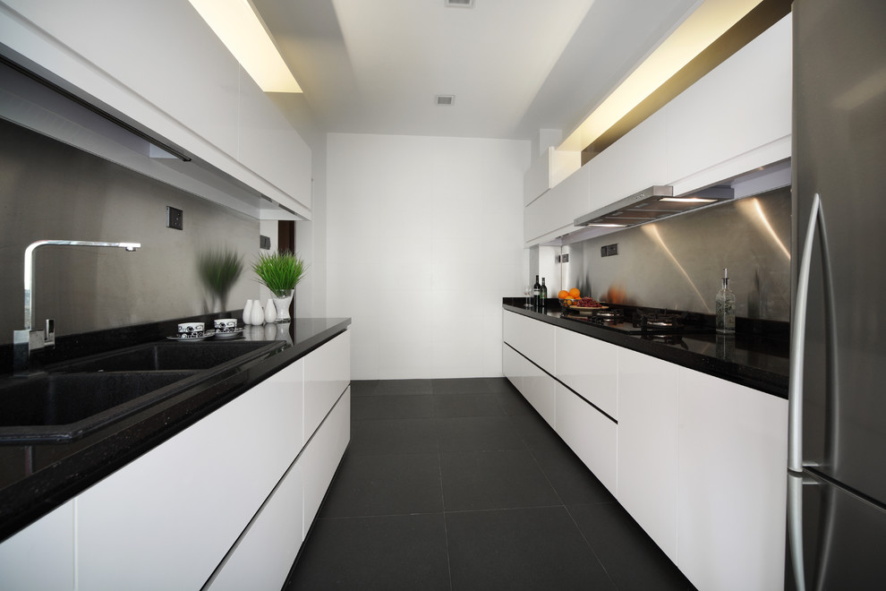 Diseño de cocina actual cerrada con fregadero encastrado, armarios con paneles lisos, salpicadero metalizado, salpicadero de metal, suelo negro y con blanco y negro