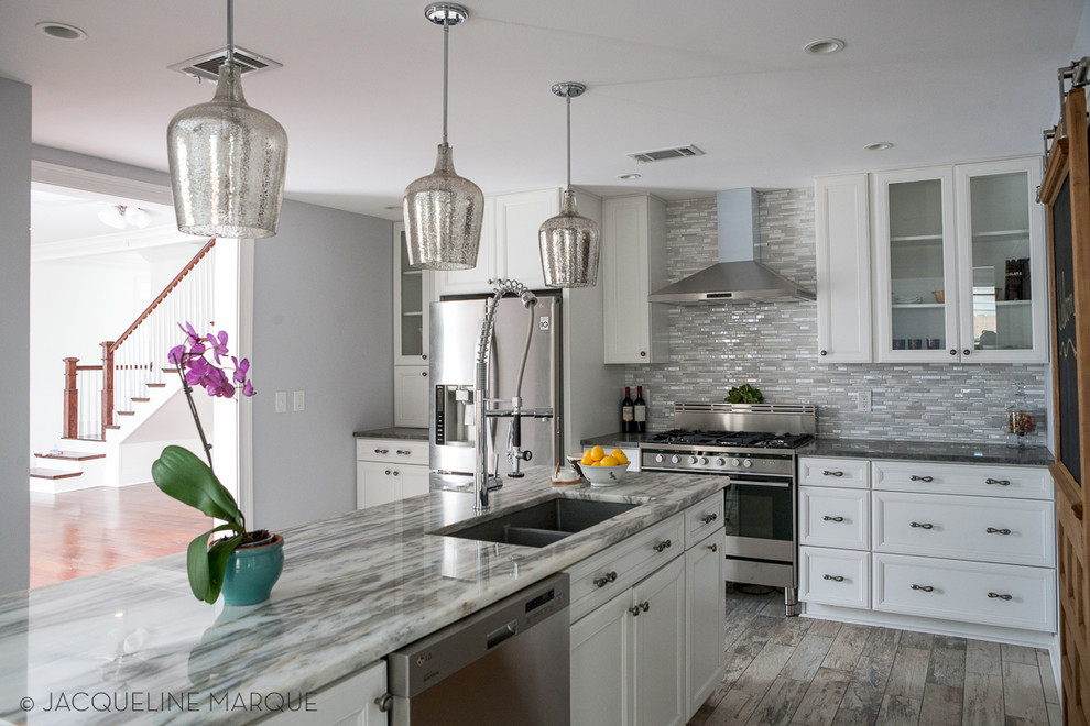 Example of a mid-sized transitional l-shaped ceramic tile eat-in kitchen design in New Orleans with an undermount sink, recessed-panel cabinets, white cabinets, marble countertops, metallic backsplash, stone tile backsplash, stainless steel appliances and an island