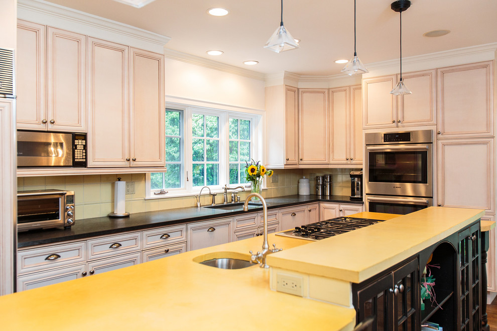 Große Retro Küche in L-Form mit Schrankfronten mit vertiefter Füllung, Küchenrückwand in Gelb, Küchengeräten aus Edelstahl, braunem Holzboden und Kücheninsel in Boston