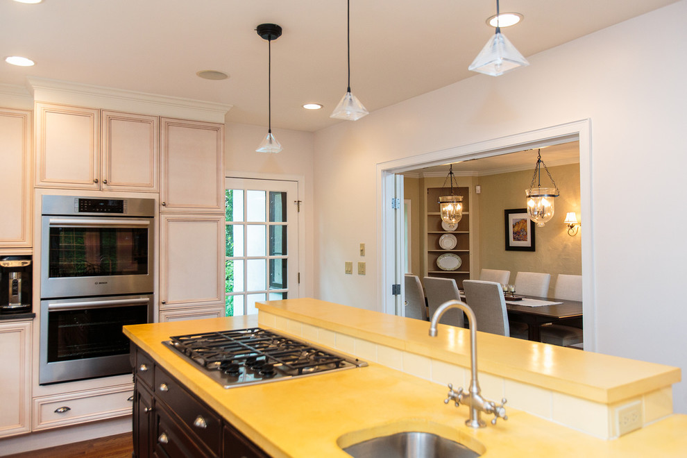 Esempio di una grande cucina moderna con ante con riquadro incassato, paraspruzzi giallo, elettrodomestici in acciaio inossidabile e pavimento in legno massello medio