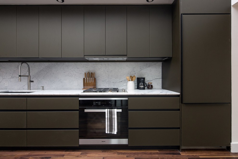 Example of a small minimalist single-wall dark wood floor and brown floor open concept kitchen design in New York with a single-bowl sink, flat-panel cabinets, black cabinets, marble countertops, white backsplash, marble backsplash, paneled appliances, no island and white countertops