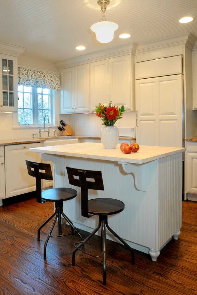 Eat-in kitchen - u-shaped eat-in kitchen idea in New York with a farmhouse sink, white cabinets, limestone countertops and paneled appliances