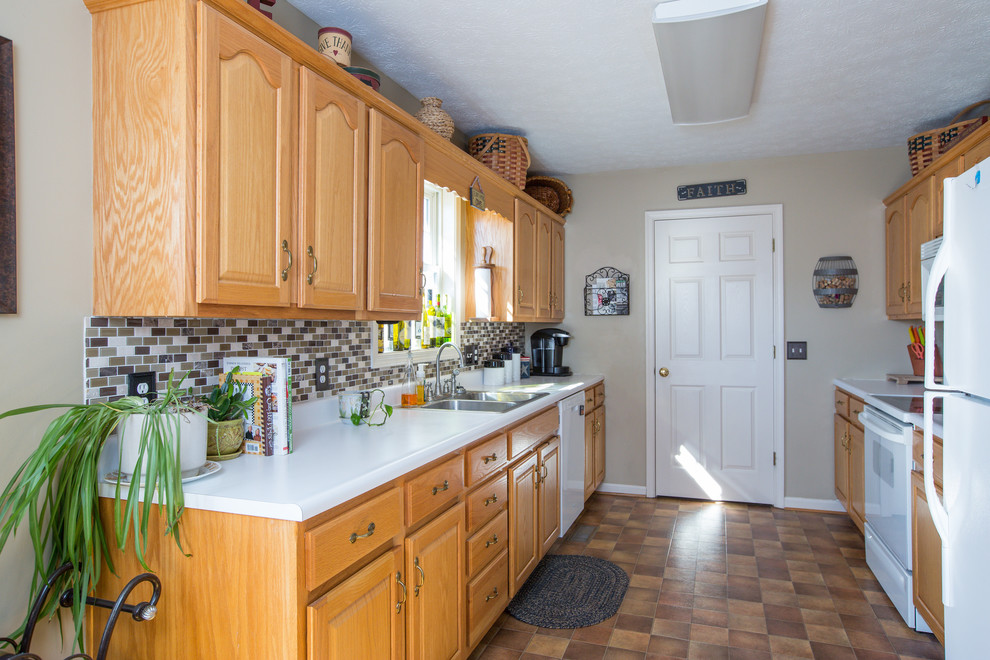 Inredning av ett klassiskt mellanstort kök, med en dubbel diskho, luckor med upphöjd panel, skåp i ljust trä, brunt stänkskydd, stänkskydd i mosaik, vita vitvaror och linoleumgolv
