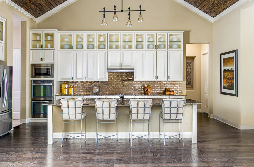 Klassische Küche in L-Form mit profilierten Schrankfronten, weißen Schränken, Küchenrückwand in Metallic, Rückwand aus Mosaikfliesen, Küchengeräten aus Edelstahl, dunklem Holzboden und Kücheninsel in Austin