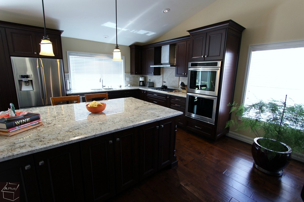 Example of a mid-sized transitional l-shaped dark wood floor eat-in kitchen design in Orange County with a double-bowl sink, recessed-panel cabinets, medium tone wood cabinets, granite countertops, gray backsplash, stone tile backsplash, stainless steel appliances and an island