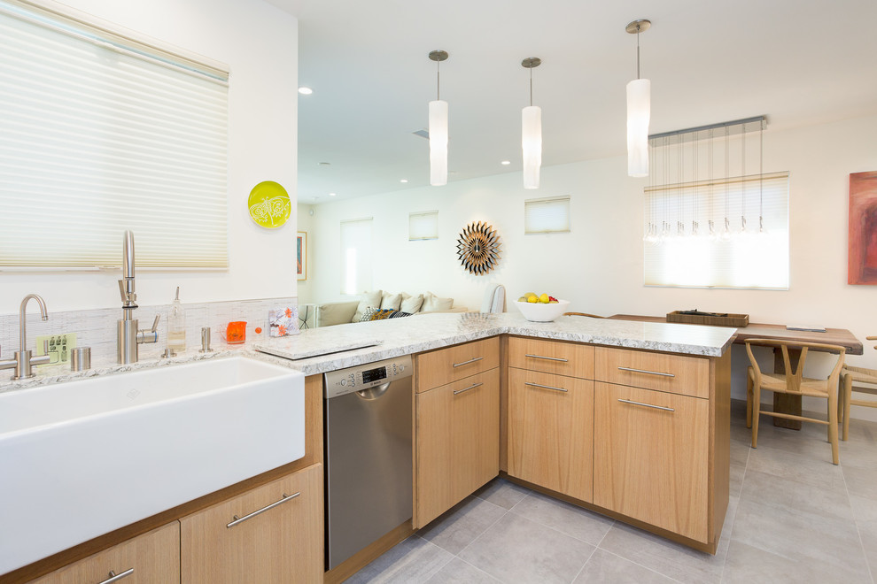 This is an example of a small modern u-shaped open plan kitchen in Orange County with flat-panel cabinets, light wood cabinets, granite worktops, a belfast sink, grey splashback, ceramic splashback, stainless steel appliances, porcelain flooring, a breakfast bar, grey floors and grey worktops.