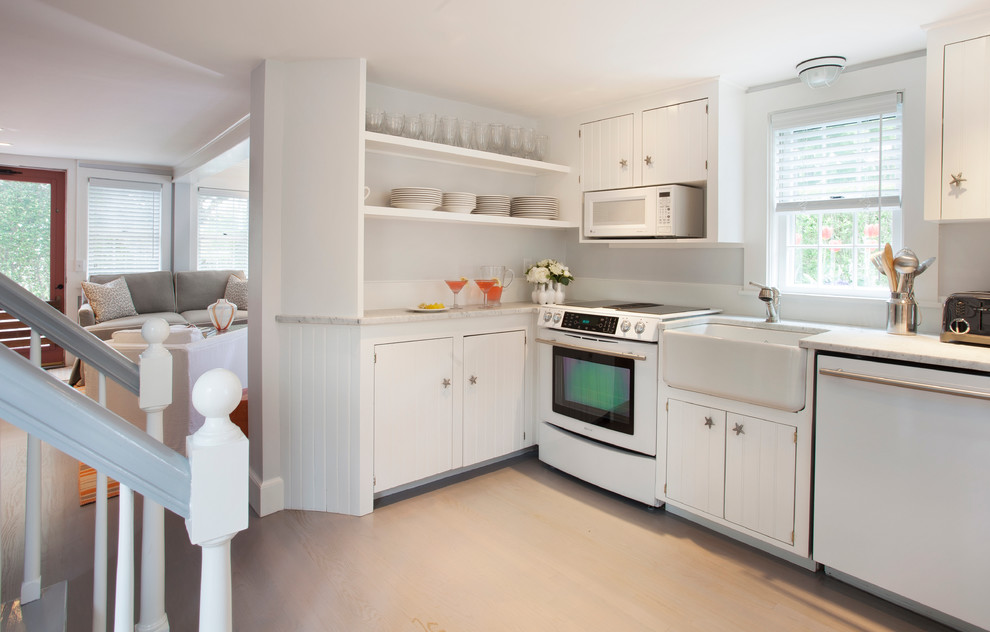 Immagine di una piccola cucina costiera con lavello stile country, ante bianche, elettrodomestici bianchi, parquet chiaro e nessuna isola