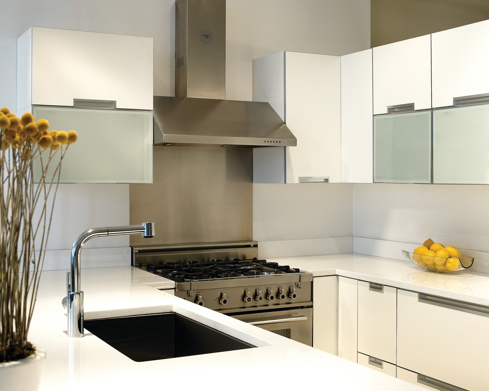 This is an example of a contemporary u-shaped kitchen in Chicago with flat-panel cabinets, a single-bowl sink, white cabinets, metallic splashback, stainless steel appliances and metal splashback.
