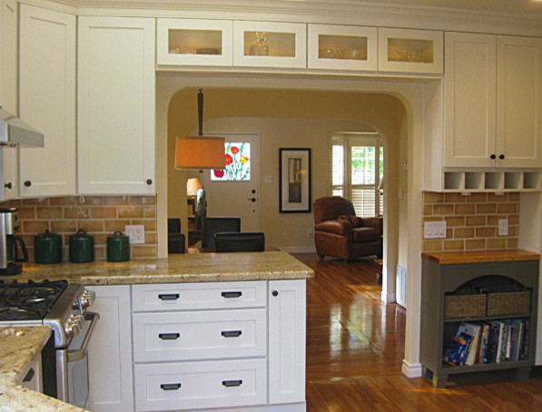 Example of a mid-sized classic l-shaped medium tone wood floor eat-in kitchen design in Philadelphia with an undermount sink, shaker cabinets, white cabinets, granite countertops, brown backsplash and stainless steel appliances