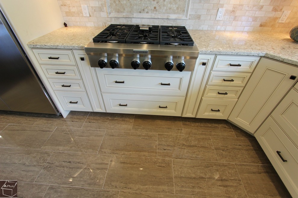 Example of a large transitional u-shaped porcelain tile eat-in kitchen design in Orange County with a double-bowl sink, recessed-panel cabinets, beige cabinets, granite countertops, beige backsplash, stone tile backsplash, stainless steel appliances and an island