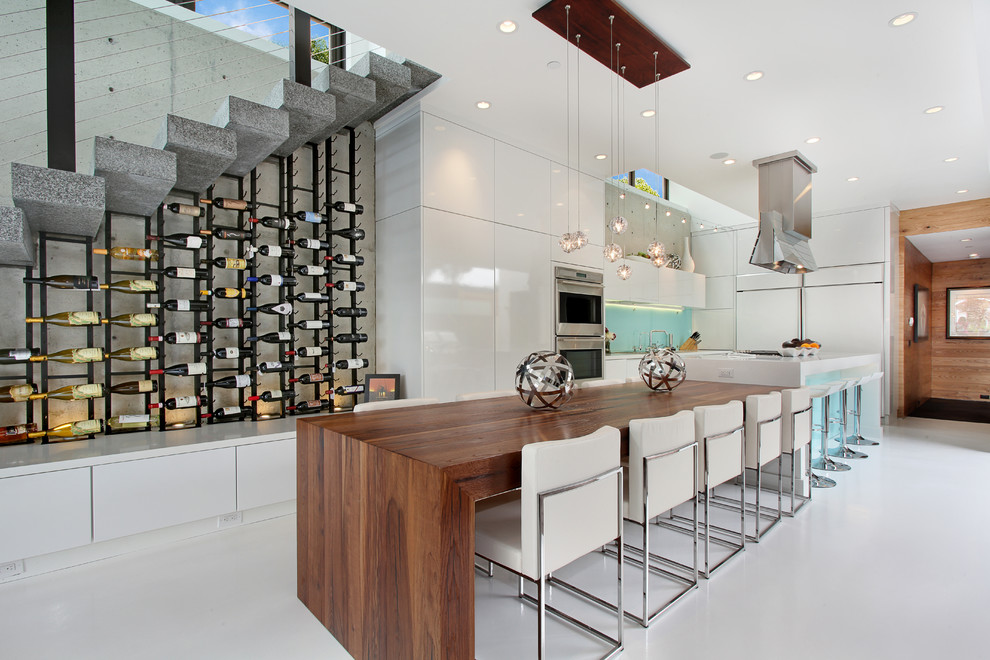 Ejemplo de cocina actual con armarios con paneles lisos, puertas de armario blancas y electrodomésticos de acero inoxidable