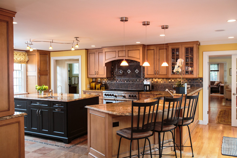 Klassische Wohnküche in U-Form mit Einbauwaschbecken, profilierten Schrankfronten, hellbraunen Holzschränken, Granit-Arbeitsplatte, Rückwand aus Glasfliesen, braunem Holzboden und zwei Kücheninseln in Boston