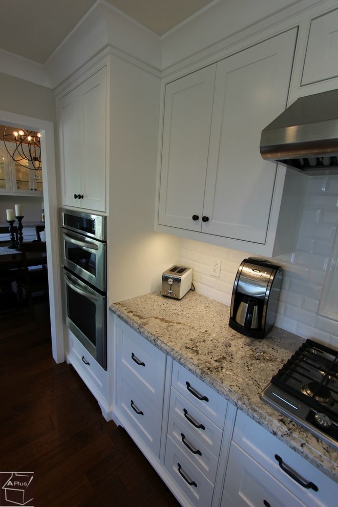 Exempel på ett mellanstort klassiskt linjärt kök och matrum, med en rustik diskho, skåp i shakerstil, vita skåp, granitbänkskiva, vitt stänkskydd, stänkskydd i tunnelbanekakel, rostfria vitvaror, mörkt trägolv och en köksö