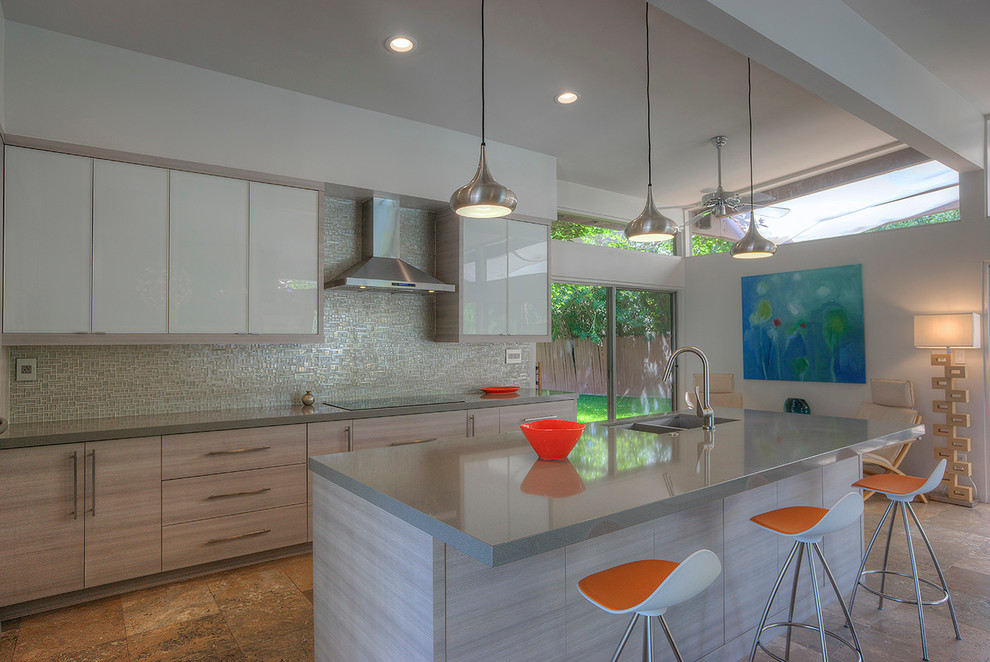 Mid-sized mid-century modern travertine floor open concept kitchen photo in Phoenix with a drop-in sink, glass-front cabinets, gray cabinets, quartz countertops, metallic backsplash, glass tile backsplash, stainless steel appliances and an island