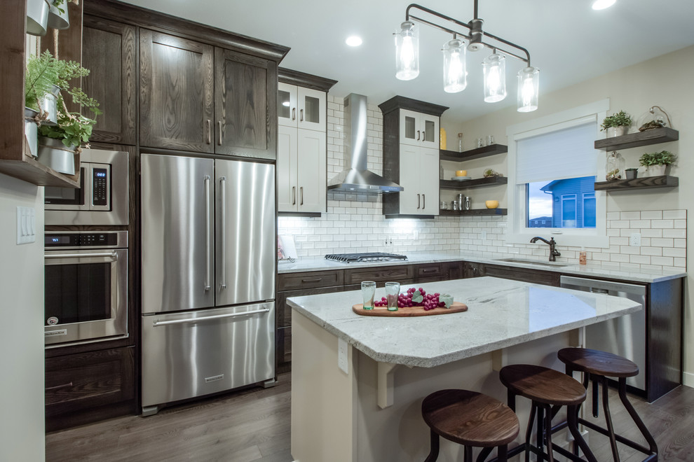 Eat-in kitchen - large traditional l-shaped laminate floor and brown floor eat-in kitchen idea in Calgary with an undermount sink, shaker cabinets, dark wood cabinets, granite countertops, beige backsplash, subway tile backsplash, stainless steel appliances and an island