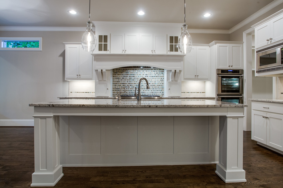 Inspiration for a modern medium tone wood floor kitchen remodel in Dallas with shaker cabinets, white cabinets, marble countertops, white backsplash, subway tile backsplash, stainless steel appliances and an island