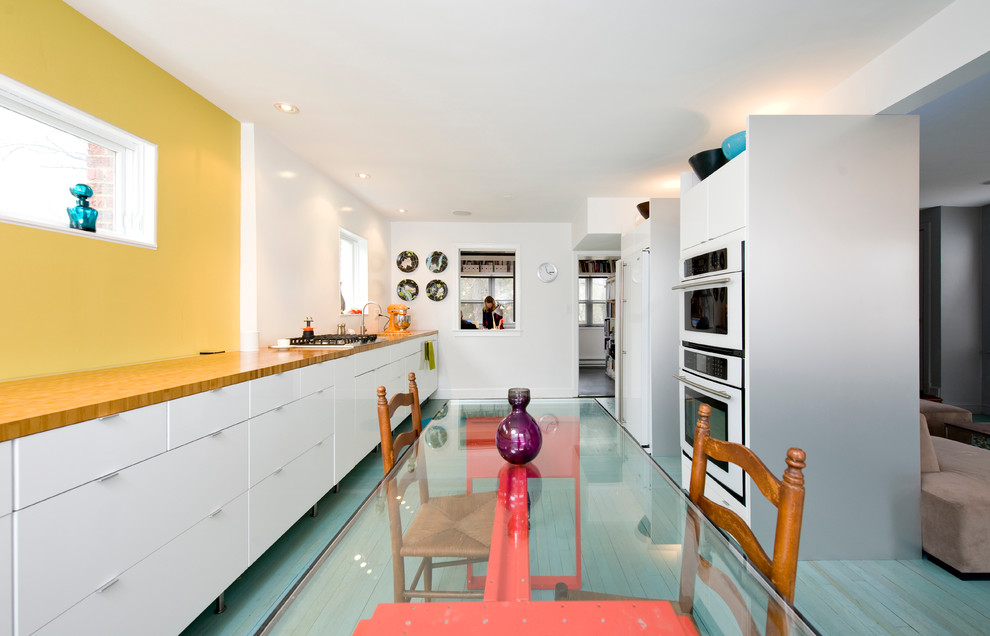 Trendy galley turquoise floor eat-in kitchen photo in DC Metro with flat-panel cabinets, white cabinets, wood countertops and white appliances