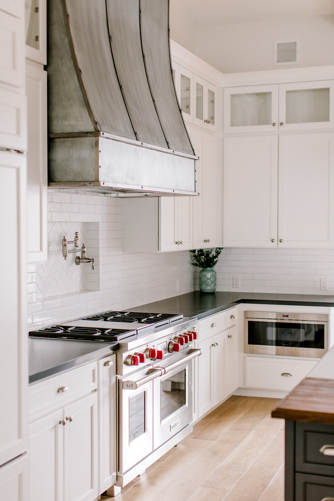 フェニックスにあるカントリー風のおしゃれなキッチン (エプロンフロントシンク、シェーカースタイル扉のキャビネット、白いキャビネット、クオーツストーンカウンター、白いキッチンパネル、レンガのキッチンパネル、シルバーの調理設備、淡色無垢フローリング) の写真