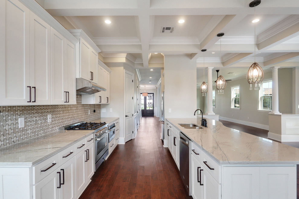 Exempel på ett stort klassiskt vit vitt kök, med en undermonterad diskho, skåp i shakerstil, vita skåp, bänkskiva i kvartsit, grått stänkskydd, stänkskydd i stenkakel, rostfria vitvaror, mellanmörkt trägolv, en halv köksö och brunt golv