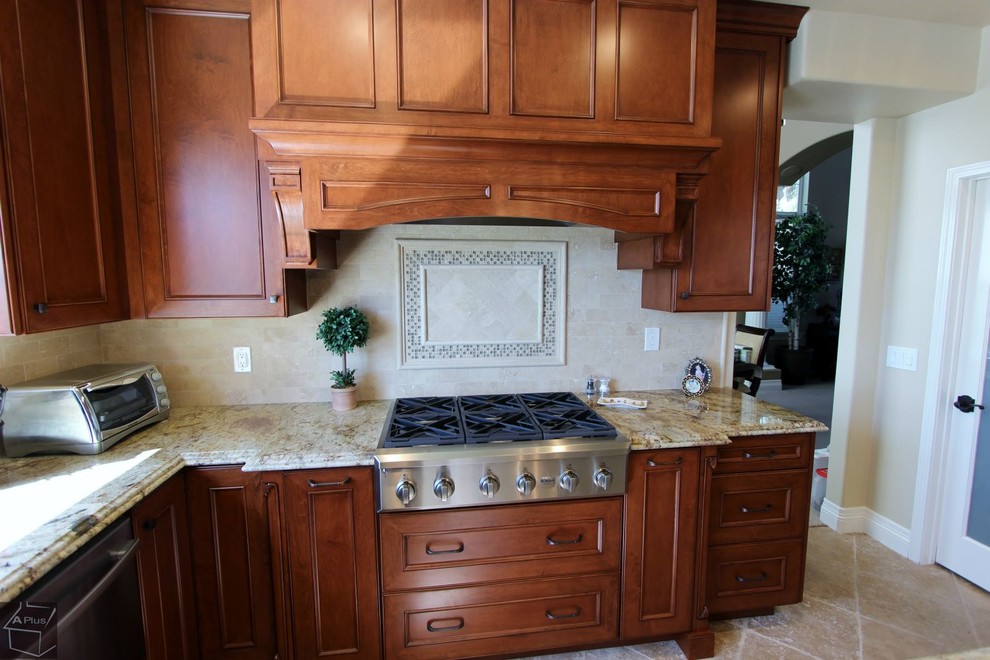Eat-in kitchen - mid-sized traditional l-shaped porcelain tile eat-in kitchen idea in Orange County with a double-bowl sink, recessed-panel cabinets, medium tone wood cabinets, granite countertops, beige backsplash, stone tile backsplash, stainless steel appliances and an island